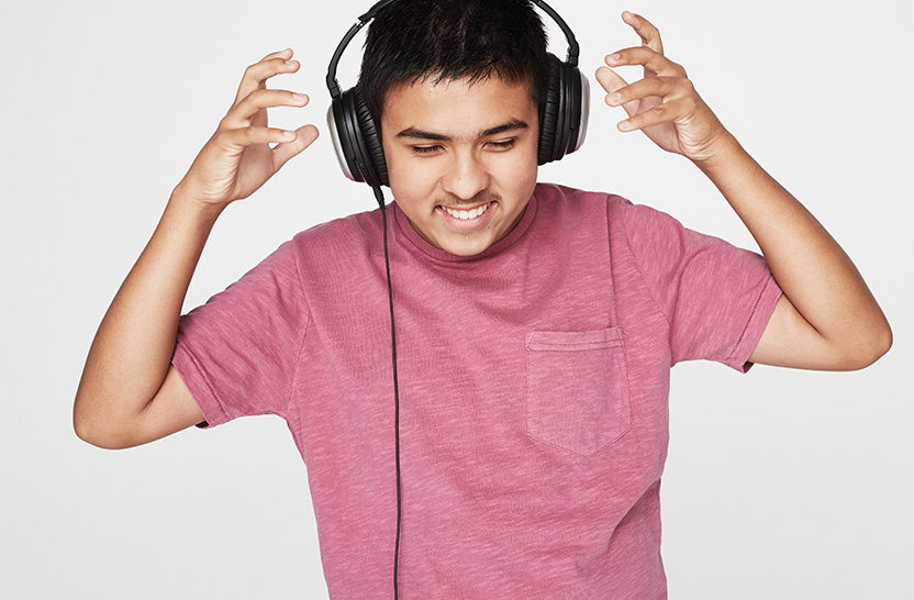 Vision Australia client smiles while adjusting over ear headphones.