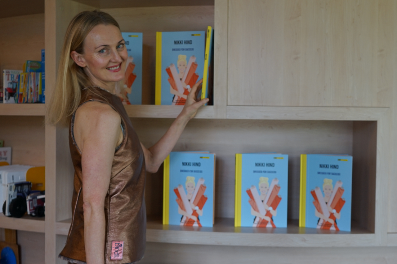 "Nikki in front of a bookshelf filled with copies of Dressed for Success."