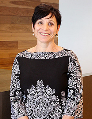 Vision Australia Chief People Officer, Simone Blumberg, smiles at the camera. She has cropped black hair and is wearing a black and white top