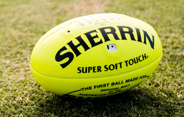 Bright yellow Sherrin audible AFL football placed on a grass field